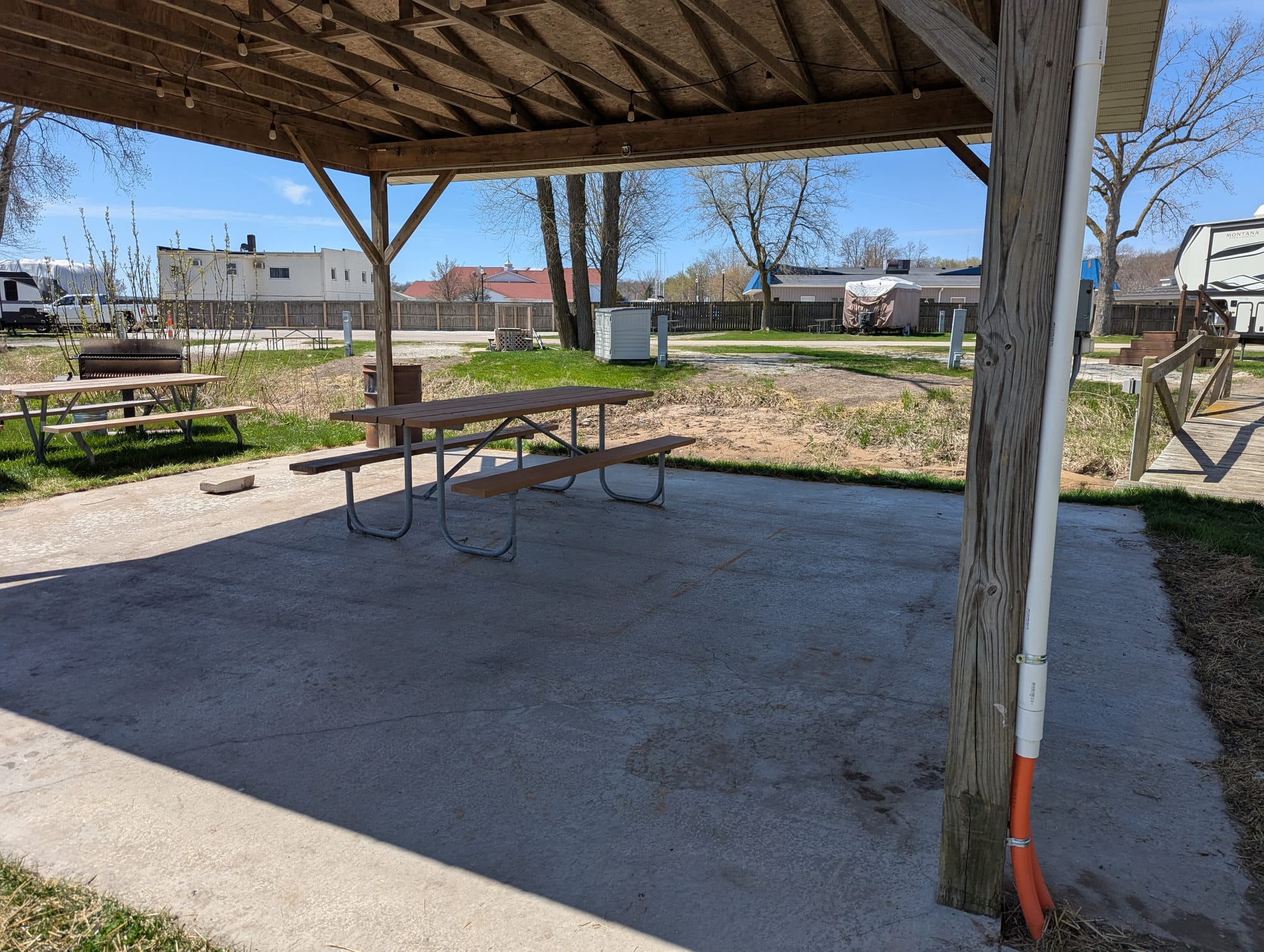 An open-walled pavilion with a concrete floor and a single picnic table under it