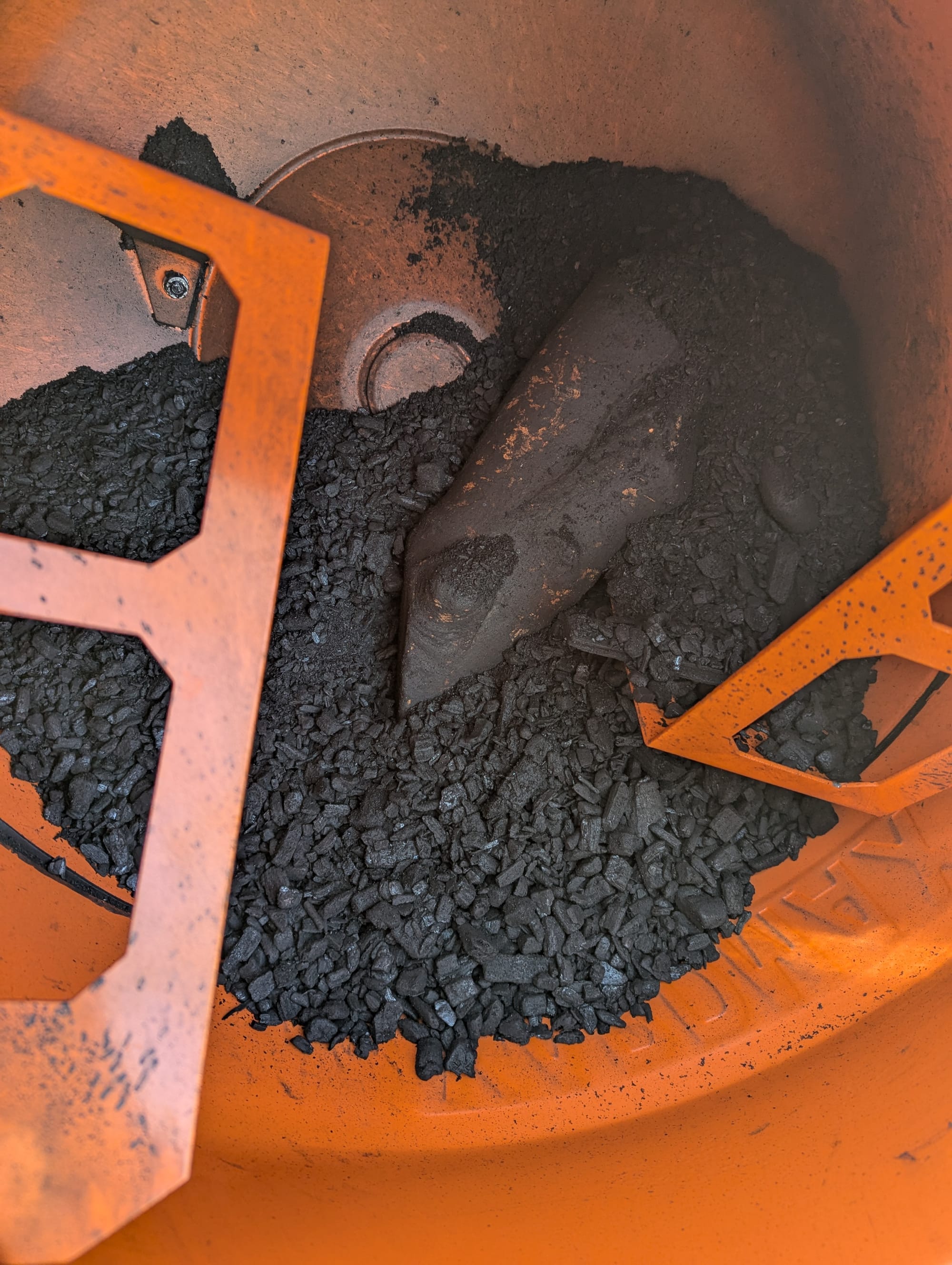 An uncropped version of the same photo from earlier with the orange cement mixer full of biochar
