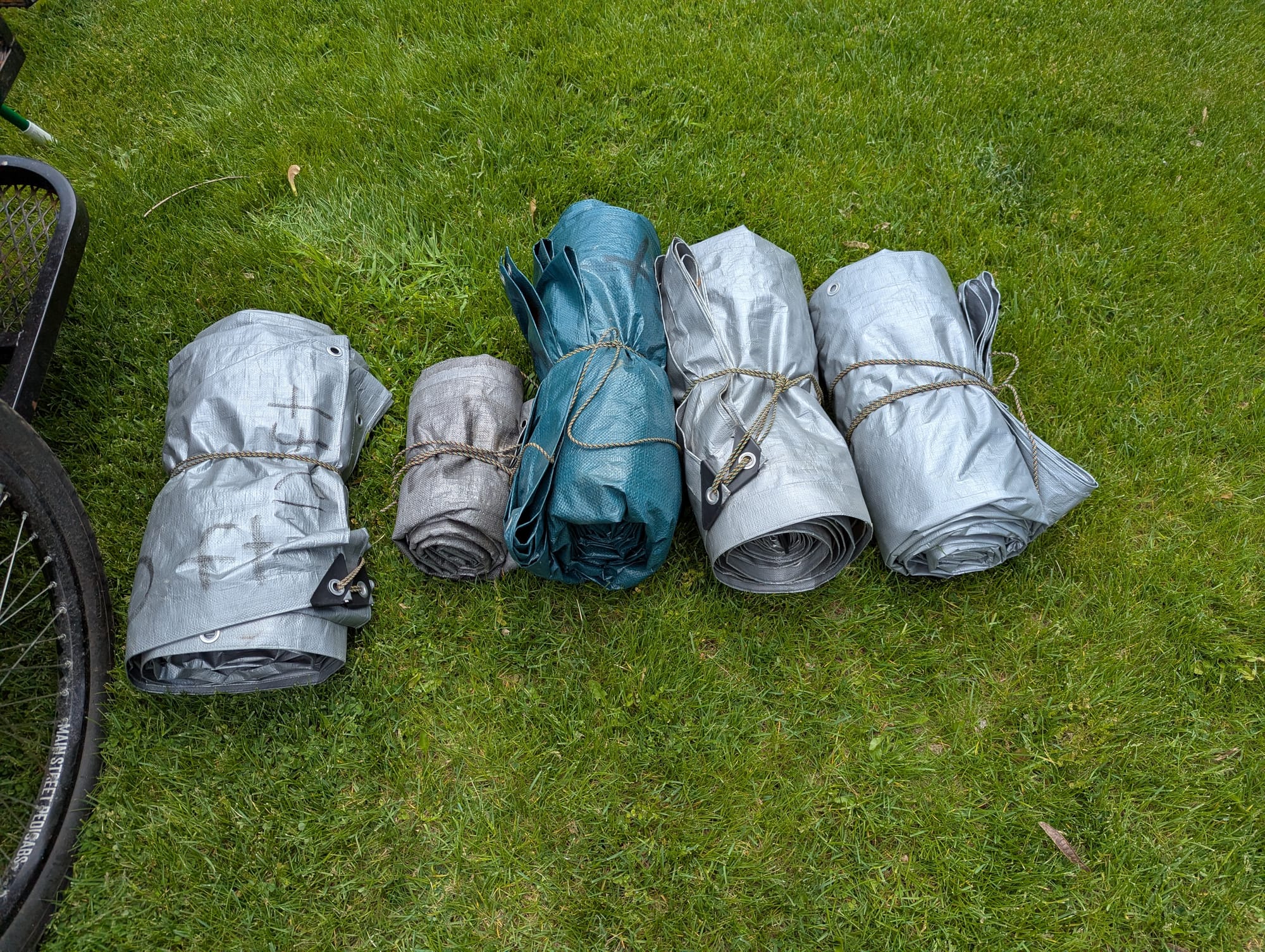 A series of 5 bundled tarps sitting in a row