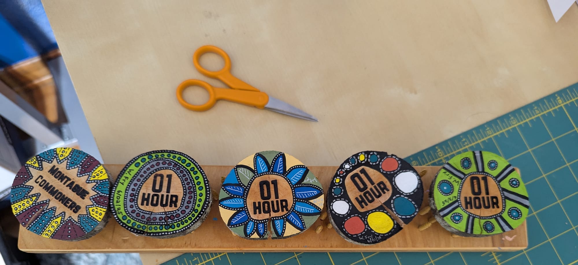 A row of five handpainted tokens representing one hour of time each