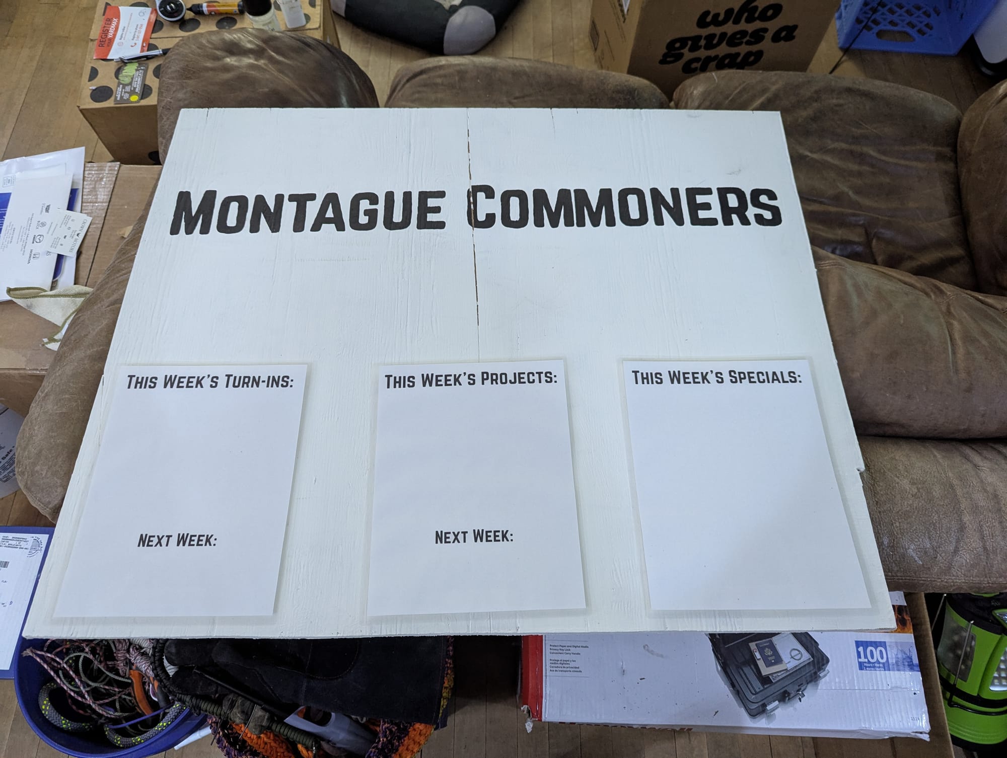 A picture of the finished sign, with the Montague Commoners lettering painted in and the weekly turn-in, project, and specials sheets attached at the bottom.