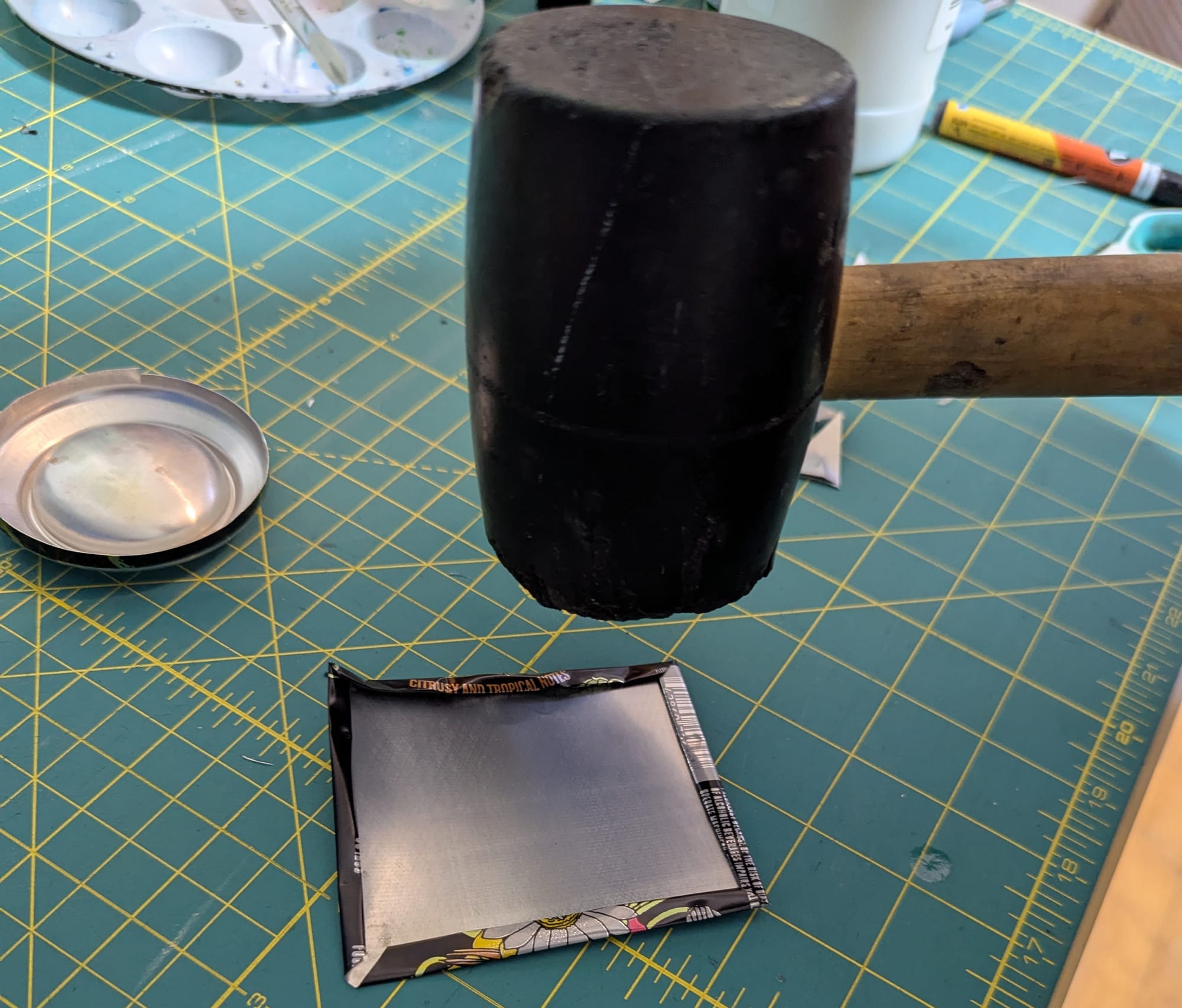 A rubber mallet poised over the tag, ready to squish the lumpy bits