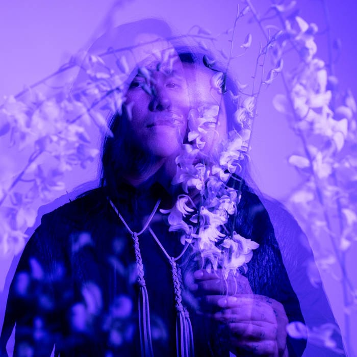 A purple album cover featuring superimposed images of singer Aysanabee, as well as plants and flowers.