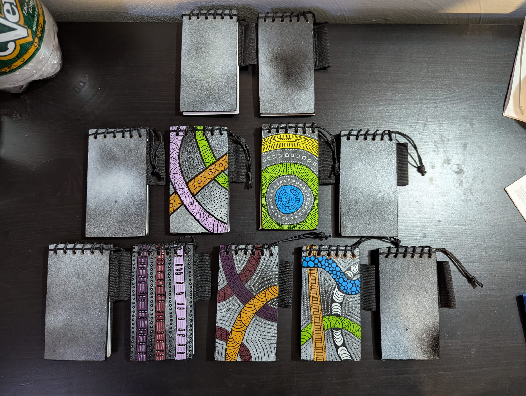 A set of 11 handmade notepads. 5 of them are elaborately handpainted, while six have simple gradient patterns