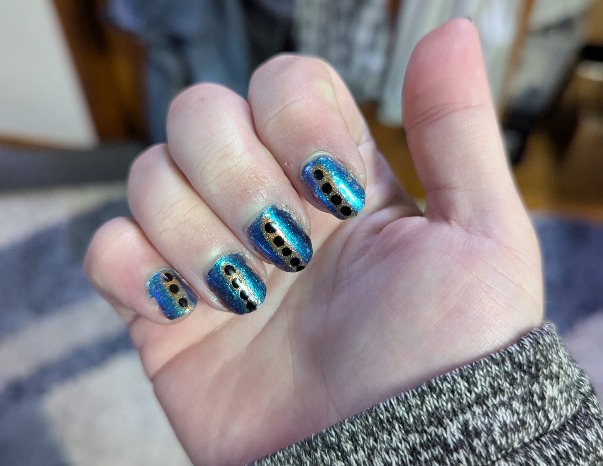Wiley's nails for this week have a turquoise holographic background with silver flakes in it, with a yellow holographic stripe down the center and black dots on top of that.