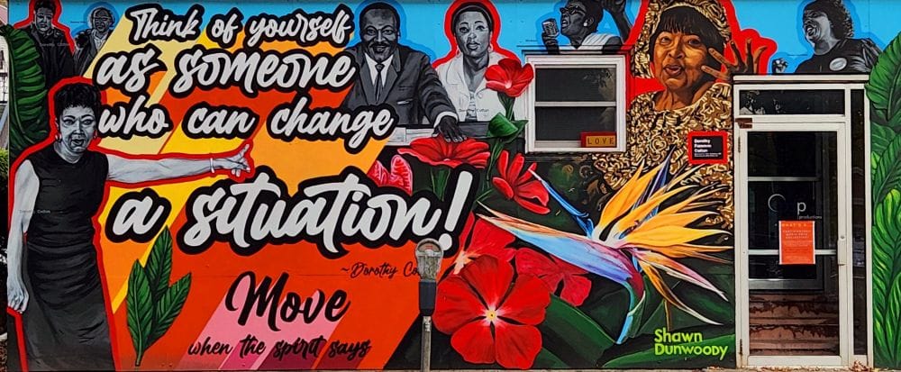 A brightly colored mural depicting major figures of the 1960s Civil Rights movement and the quote "Think of yourself as someone who can change a situation" by Dorothy Cotton.