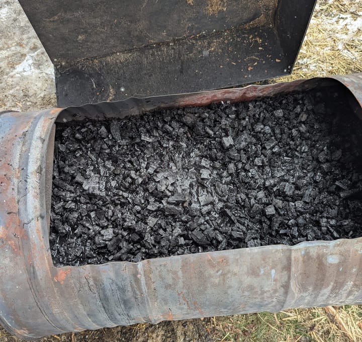 A biochar stove made from a 55 gallon steel drum that is full of charcoal floating in water