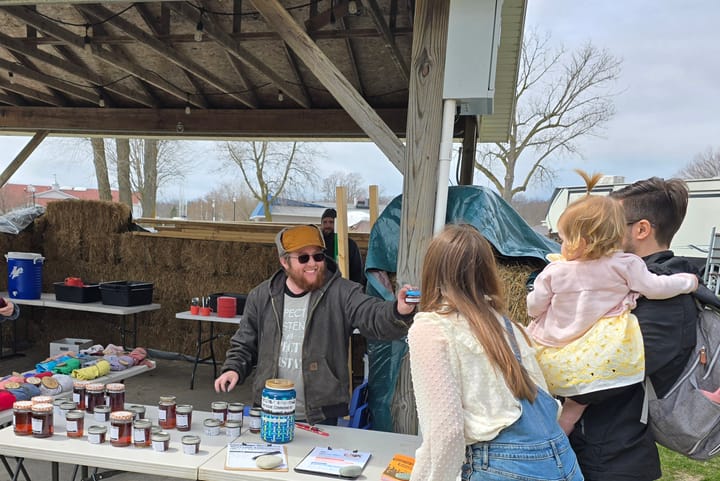 Wiley hands a 2oz jar of maple syrup to the Marks family representing baby Dillon's contribution to the sugarbush