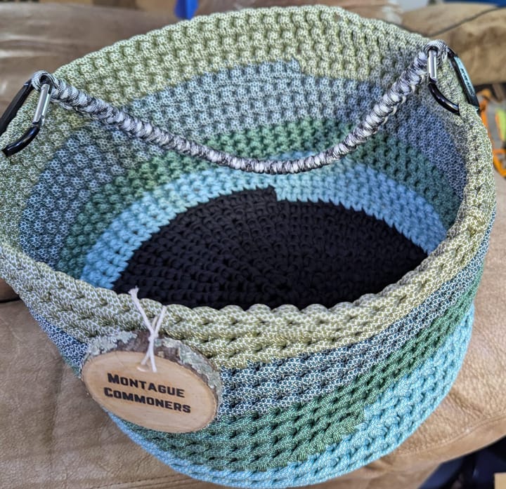A crocheted basket made from 550 Paracord. The colors are a mix of light blues and greens